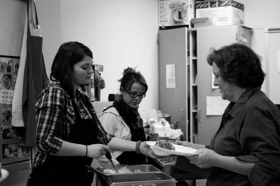 Seniors Ann Loemker and Ashlyn Boelke serve Carol Wilkerson gumbo.