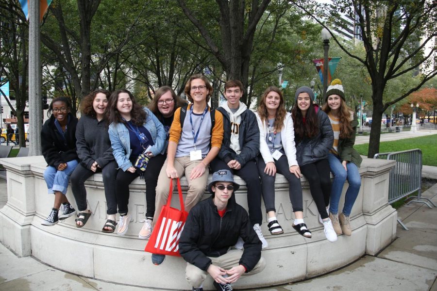 Journalism students pose on the sign in front of Millennium Park