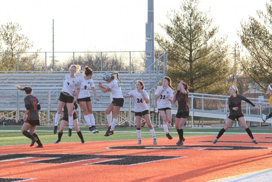 Three varsity girls soccer players jump to head the ball off of a corner kick on March 16.