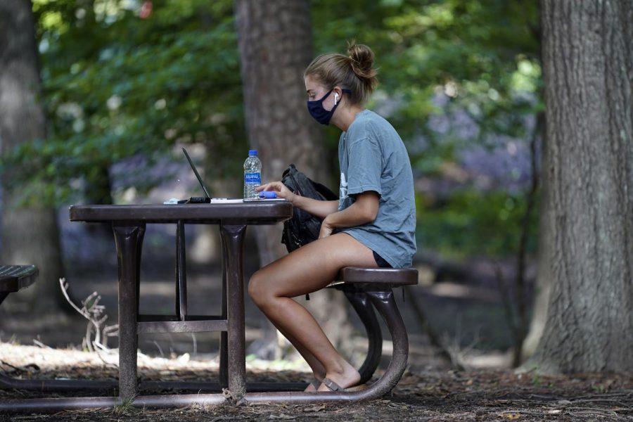 A student works outside of Ehrighaus dormitory at the University of North Carolina in Chapel Hill, Tuesday, Aug. 18, 2020. 