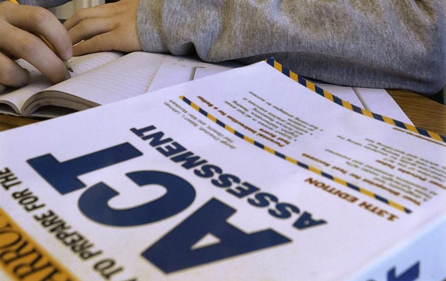 A student sits before an ACT preparation book. The MyACT website currently offers the guides for about $40.