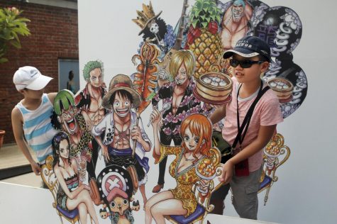 Visitors pose with cut-out comic characters, created by Japanese manga artist Eiichiro Oda, displayed at an exhibition in Taipei, Taiwan, Sunday, Aug. 24, 2014. The exhibition showcase the work of Oda who is best known for his manga series Once Piece.