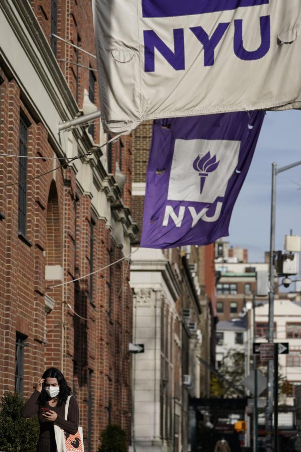 A woman wears a mask as she walks under NYU banners in New York, Thursday, Dec. 16, 2021.