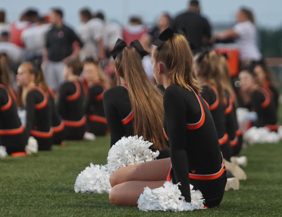 The cheer team sits along the sidelines of an August 20 football scrimmage.