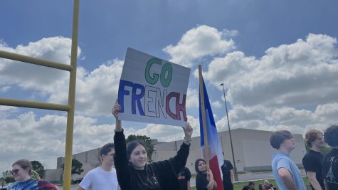 Senior Ivanna Gonzalez, a French student, holds up a sign during the kickball game against the German students on May 9. The sign was signed by most of the French students on the back during the game.