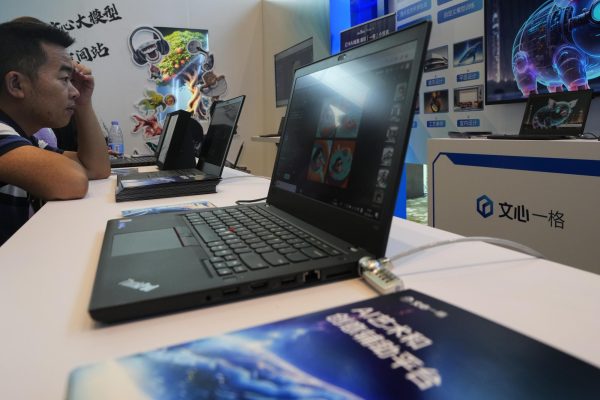 A visitor checks out the AI chatbot Ernie Bot via a laptop computer at a booth promoting the AI chatbot during the Wave Summit in Beijing on Aug. 16, 2023. Chinese search engine and artificial intelligence firm Baidu on Thursday made its ChatGPT-equivalent language model available to the public, in a sign of a green light from Beijing which has in recent months taken steps to regulate the industry. 