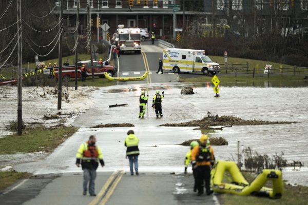 First responders stand in the floodwaters of the Perkiomen Creek at Graterford Road in Collegeville, Pa., Monday, Dec. 18, 2023