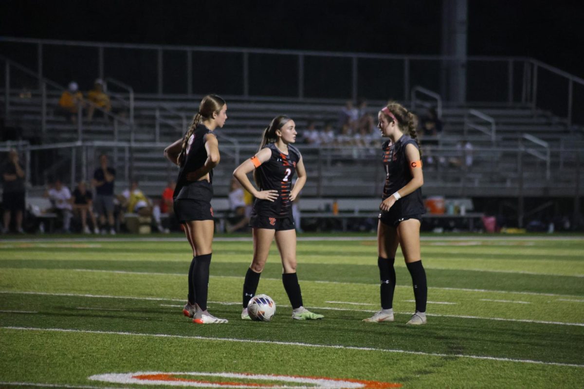 Junior Mea Hook talks to junior Blakely Hockett and senior Kylie Peel during the April 15 loss to O'Fallon.